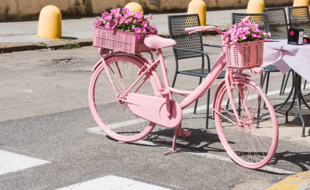 bici rosa con fiori parcheggiati per strada - giro ditalia foto e immagini stock