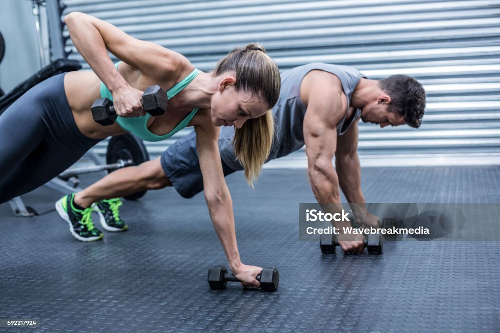 Muscular couple doing plank exercise together Muscular couple doing plank exercise while lifting weights 30-34 Years Stock Photo