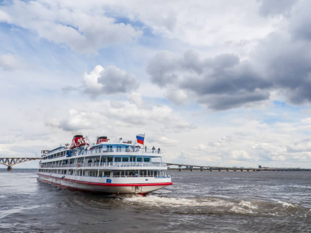 4 갑판 여객선 사라토프 시의 부두에서 출발합니다. 에 지평선도로 교량. 볼가 강, 러시아. 푸른 하늘에 흰 구름 - cruise ship river ship passenger ship 뉴스 사진 이미지