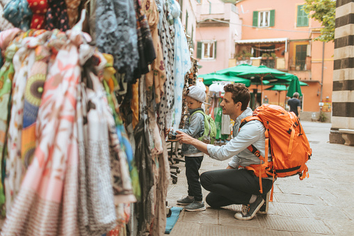 Photo of a tourists, father and son, shopping souvenirs while exploring vivid streets of Italian villages together