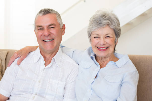 istock Retired couple sitting on couch smiling at camera 692233862