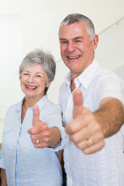 istock Cheerful retired couple looking at camera giving thumbs up 692234448