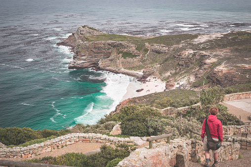 Tourist hiking at Cape Point, looking at view of Cape of Good Hope and Dias Beach, travel destination in South Africa. Table Mountain National Park, Cape Peninsula. Toned image.