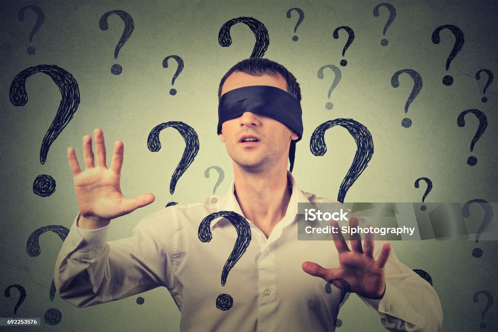 blindfolded man stretching his arms out walking through many question marks Portrait blindfolded man stretching his arms out walking through many question marks Blindfold Stock Photo