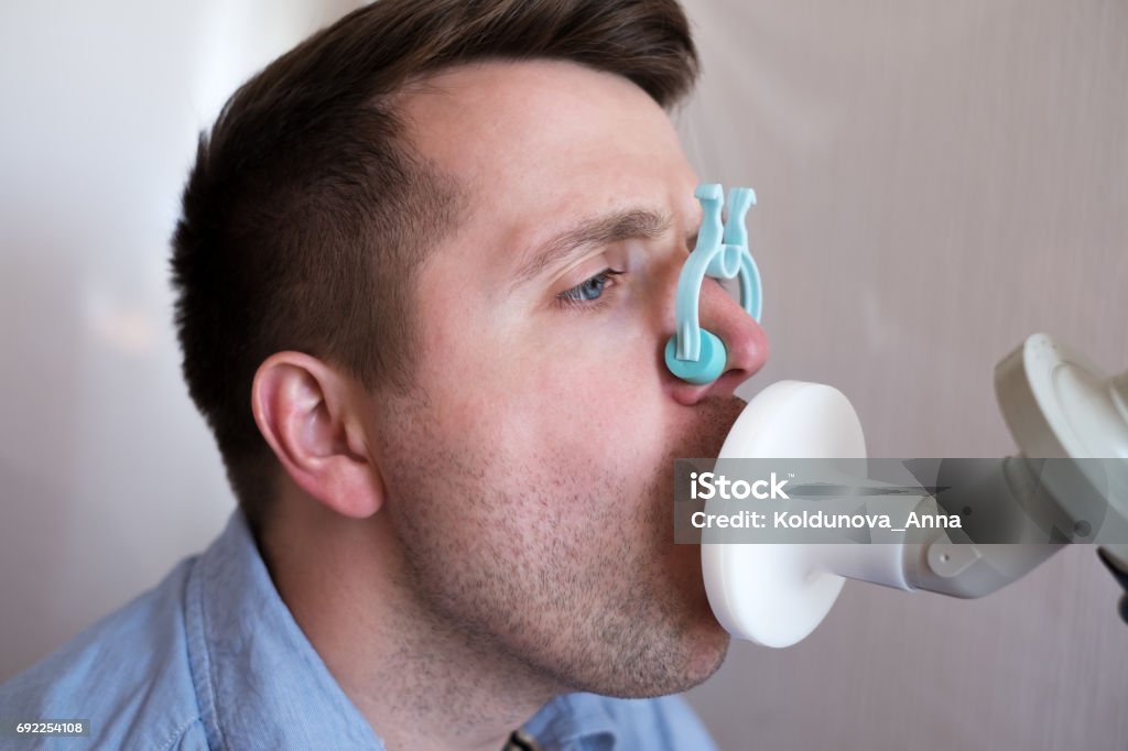 Young man testing breathing function Young man testing breathing function by spirometry Spirometer Stock Photo