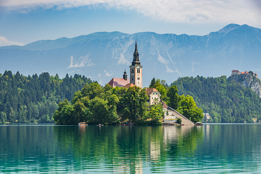 Beautiful Lake Bled in Slovenia. 'Church dedicated to the Assumption of Mary' - Santa Maria Church with surrounding houses and clock tower in the middle of small islet in the famous slovenian lake. Alps in the background. Lake Bled, Slovenia, Europe