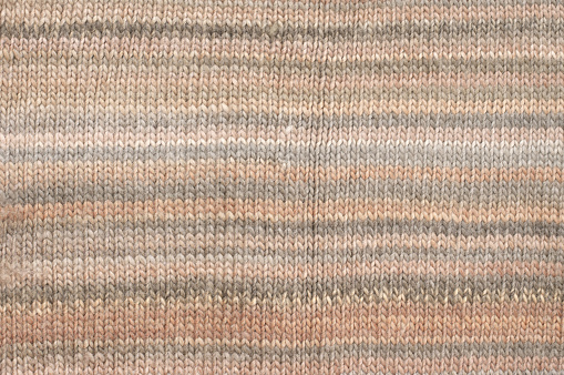 Knitted cloth plain stitch texture of melange beige and brown colored woolen yarn.