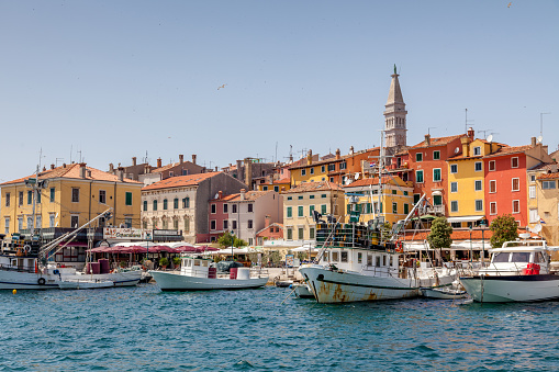 Famous and colorful Rovinj harbor waterfront with tourist boats, fisherboats, restaurants, shops and colorful houses. Church of St. Euphemia in the background on the top. Rovinj - Rovigno, Istria, Croatia, Europe.