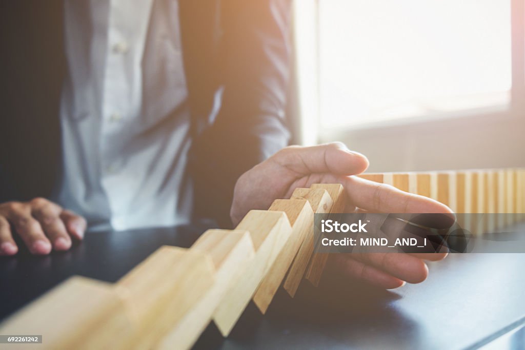 Problem Solving,Close up view on hand of business woman stopping falling blocks on table for concept about taking responsibility. Risk Stock Photo