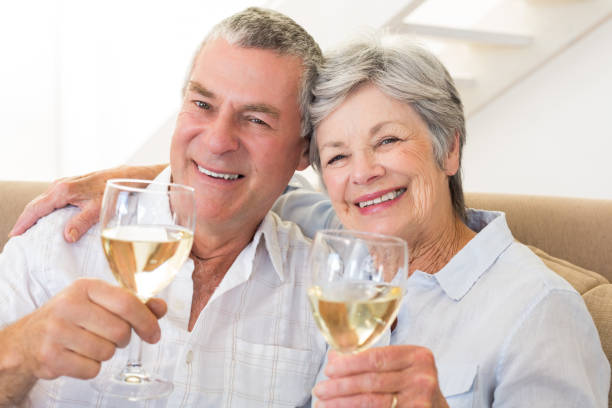 istock Senior couple sitting on couch having white wine 692267004