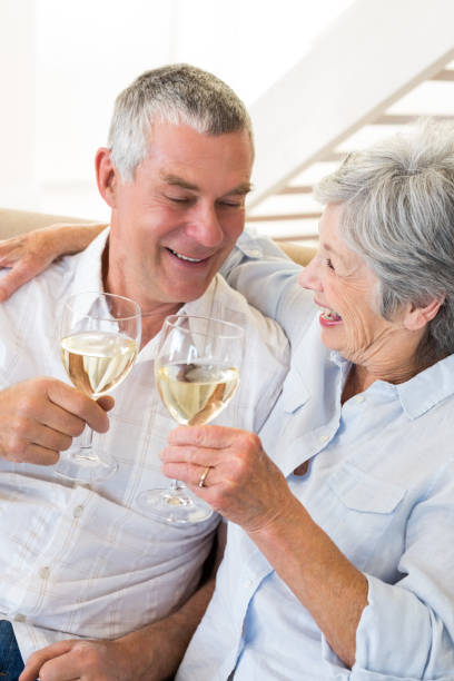 istock Senior couple sitting on couch having white wine 692267288