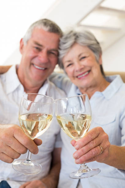 istock Senior couple sitting on couch having white wine 692267418