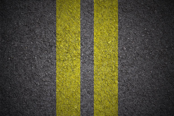 istock Road with yellow double lines close up - background texture 692283424