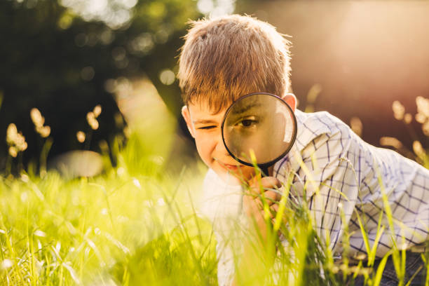 istock Happy little boy looking through magnifying glass 692286090