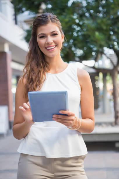 istock Portrait of smiling woman using tablet computer and looking at camera 692286874