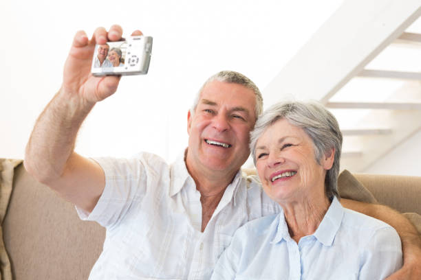 istock Senior couple sitting on couch taking a selfie 692289264