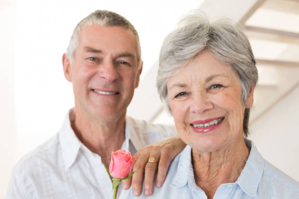 istock Senior man offering a rose to his partner smiling at camera 692292358