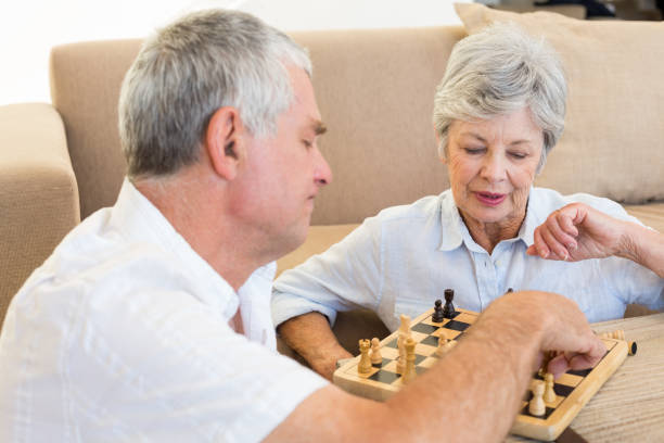 istock Senior couple sitting on floor playing chess 692293086