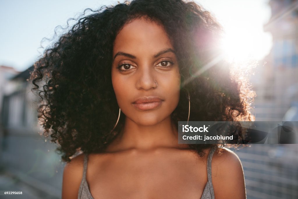 Afro american female standing outdoors Close up portrait of beautiful young african woman with curly hair. Afro american female standing outdoors. Women Stock Photo