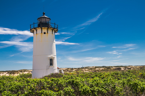 The tower of the Race Point Lighthouse at the tip of Cape Cod stands against a deep blue springtime sky.