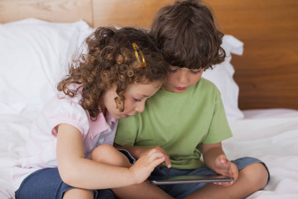 istock Boy and girl using digital tablet in bed 692322248