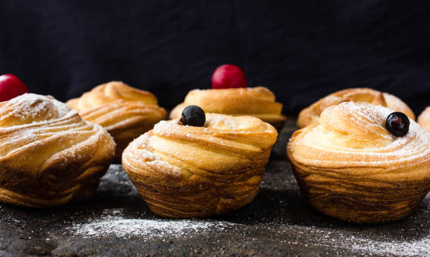 istock Cruffins - Buns from yeast dough. Dark background. Mystical light. cinnamon craffin (cinnabon) (mix of croissant and muffin) 692324850