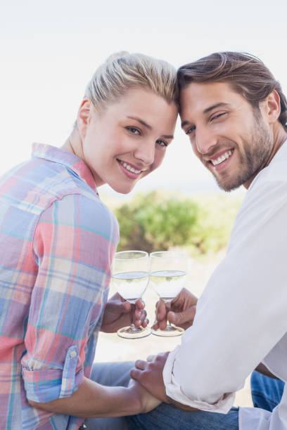 istock Happy couple smiling at camera holding wine glasses 692328134