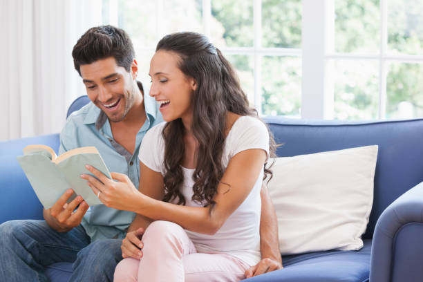 istock Attractive couple reading book on the sofa 692328542