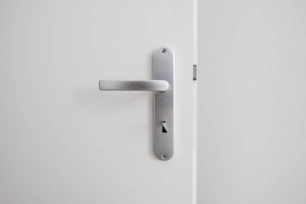 metalen deurklink met sleutel op witte deur - deurknop stockfoto's en -beelden