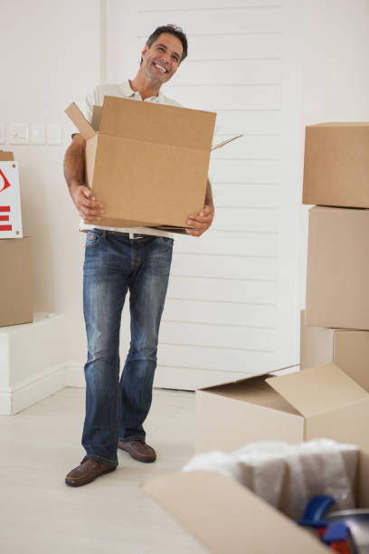 istock Smiling man carrying boxes in new house 692347188