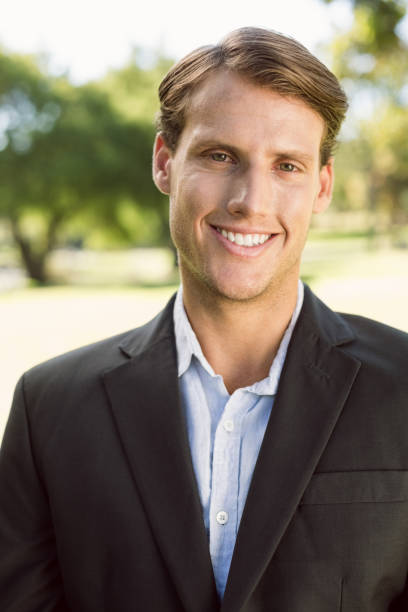 istock Handsome businessman in the park smiling at camera 692354050