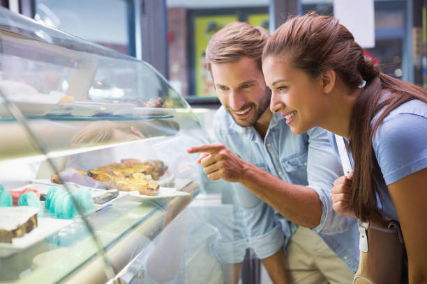 young happy couple choosing cake - cake pick imagens e fotografias de stock