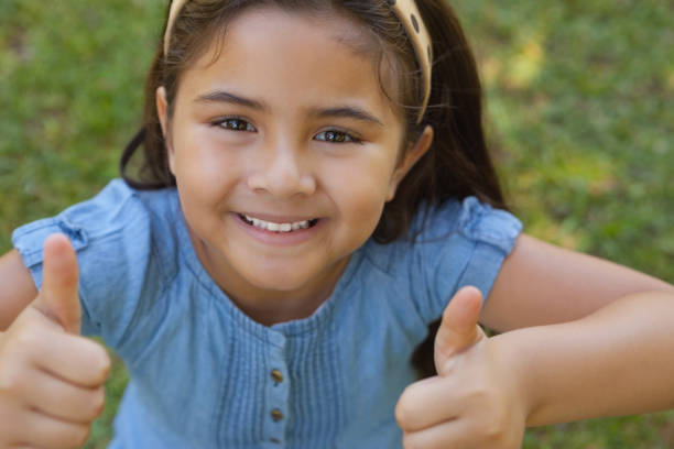 istock Young girl gesturing thumbs up at park 692368180