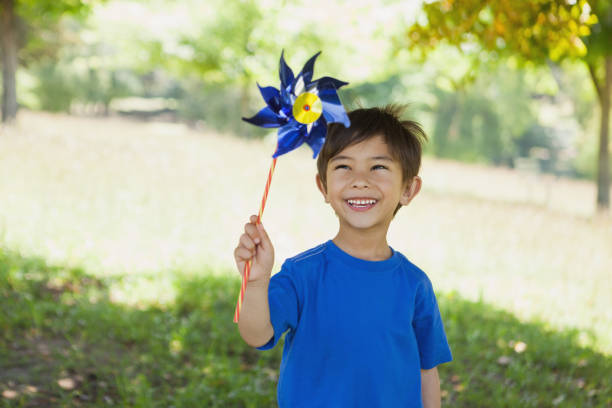 heureux mignon petit garçon tenant pinwheel au parc - moulinet jouet photos et images de collection