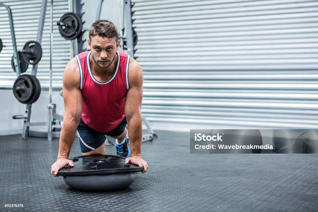 Portrait of muscular man using bosu ball Portrait of muscular man using bosu ball in gym 20-29 Years Stock Photo