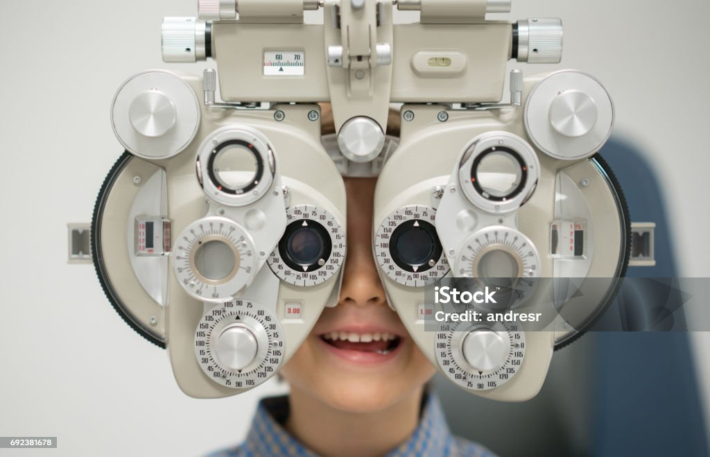 Young patient getting an eye exam at the optician Young patient getting an eye exam at the optician on the phoropter â healthcare and medicine concepts Child Stock Photo