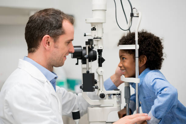 boy getting an eye exam at the optician - patient happiness cheerful optometrist imagens e fotografias de stock