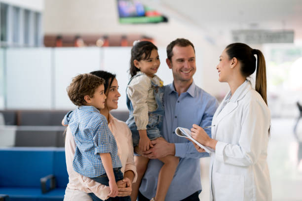 Doctor talking to a family at the hospital Doctor talking to a happy Latin American family at the hospital - healthcare and medicine concepts lab coat photos stock pictures, royalty-free photos & images