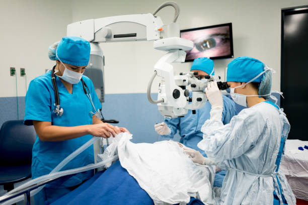 Ophthalmic surgeon performing an eye surgery at the hospital Ophthalmic surgeon performing an eye surgery at the hospital with a microscope - healthcare and medicine concepts eye surgery photos stock pictures, royalty-free photos & images