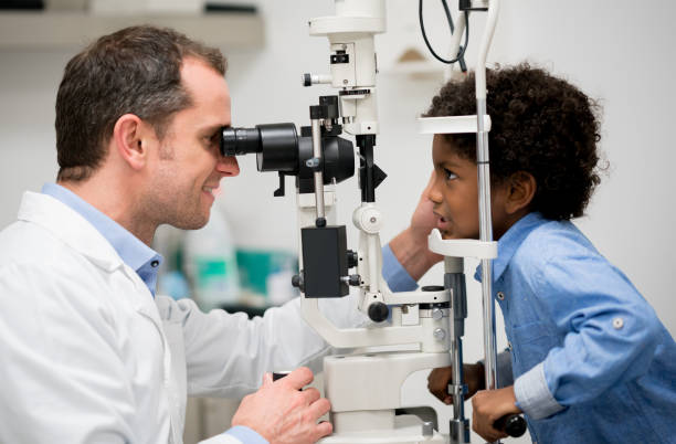 Boy getting an eye exam at the optician Happy Latin American boy getting an eye exam at the optician on the phoropter - healthcare and medicine concepts eye exam stock pictures, royalty-free photos & images