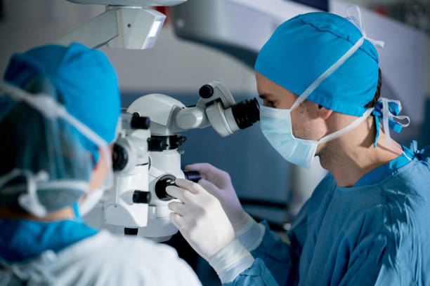 Surgeons performing an eye surgery under the microscope Surgeons performing an eye surgery under the microscope at the hospital - healthcare and medicine concepts eye surgery photos stock pictures, royalty-free photos & images