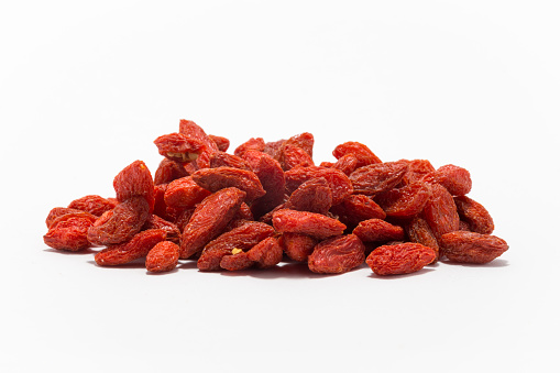 Red berries in a pile on a flat surface and white background