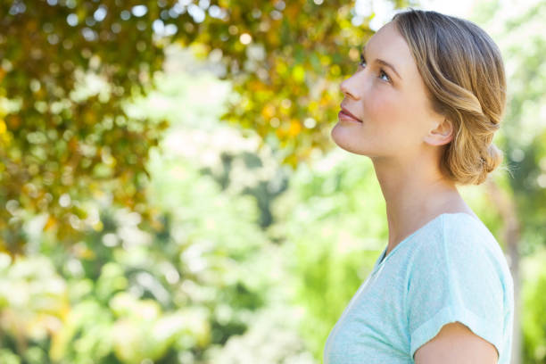 istock Serious young woman looking at leaves in park 692409048