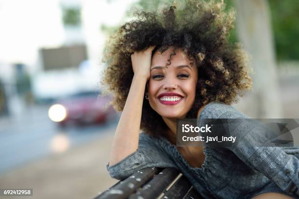 Young Black Woman With Afro Hairstyle Smiling In Urban Background Stock Photo - Download Image Now