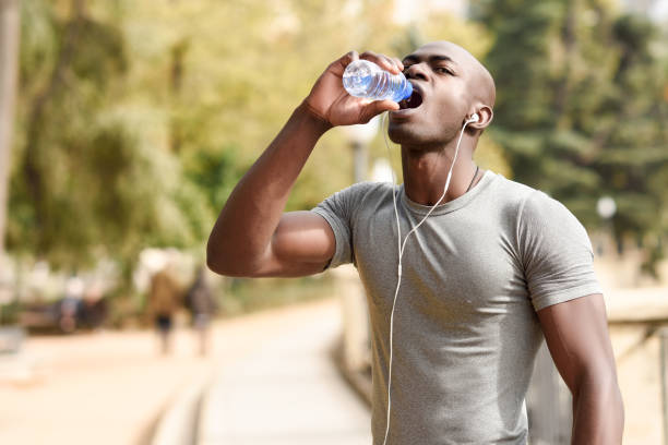 istock Young black man drinking water before running in urban background 692416088