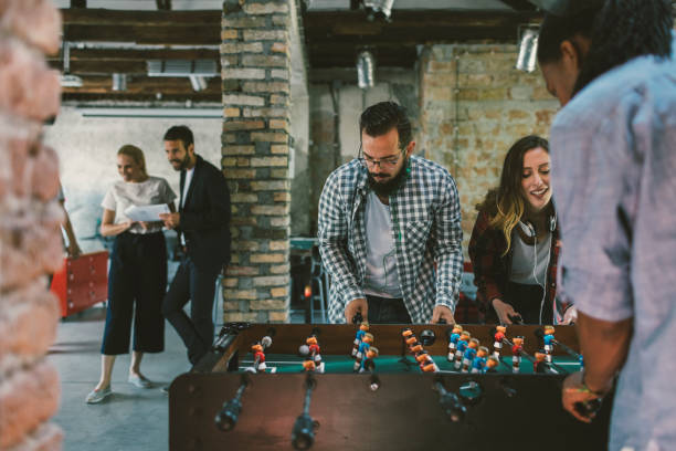 Coworkers playing foosball on break. They are having fun on break and enjoying the game