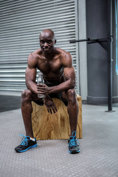 istock Young Bodybuilder sitting on a wooden Block 692442212