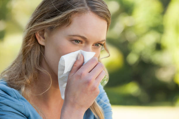 istock Woman blowing nose with tissue paper at park 692445256