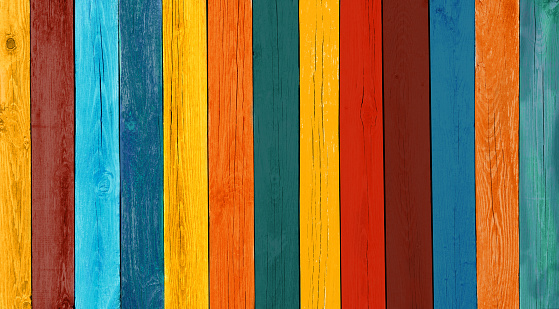 Art Wooden Background. Creative Colorful Wallpaper. Restored old wooden Texture. Wood Surface Fence Panel with boards painted Multicolored Paint, Close-up. Wide Horizontal Image with Copy Space