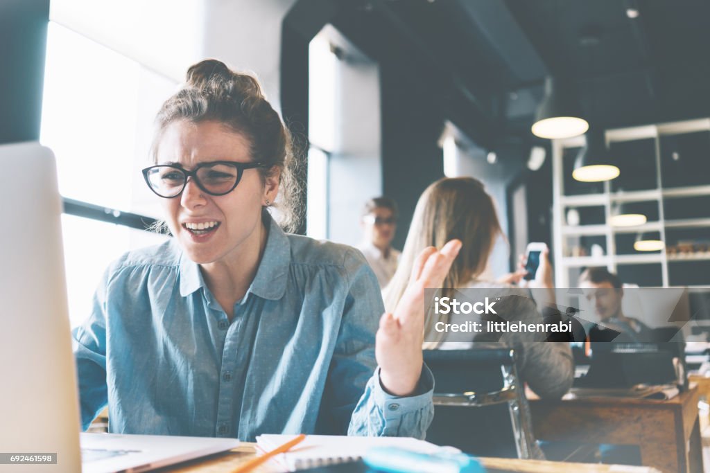 Emotional business lady shouting at her laptop Emotional business lady sitting disappointed. Hard stressfull workday in the office. Bad news from the laptop Anger Stock Photo